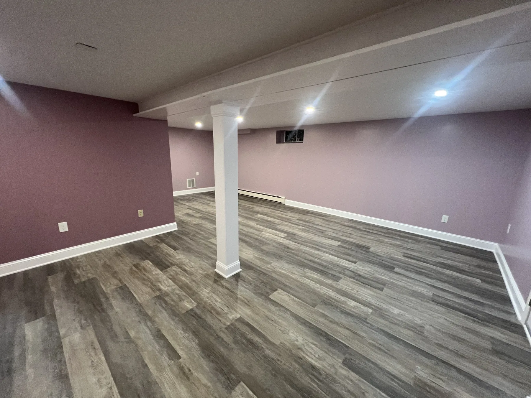 Finished basement with plank flooring, painted walls and recessed lighting