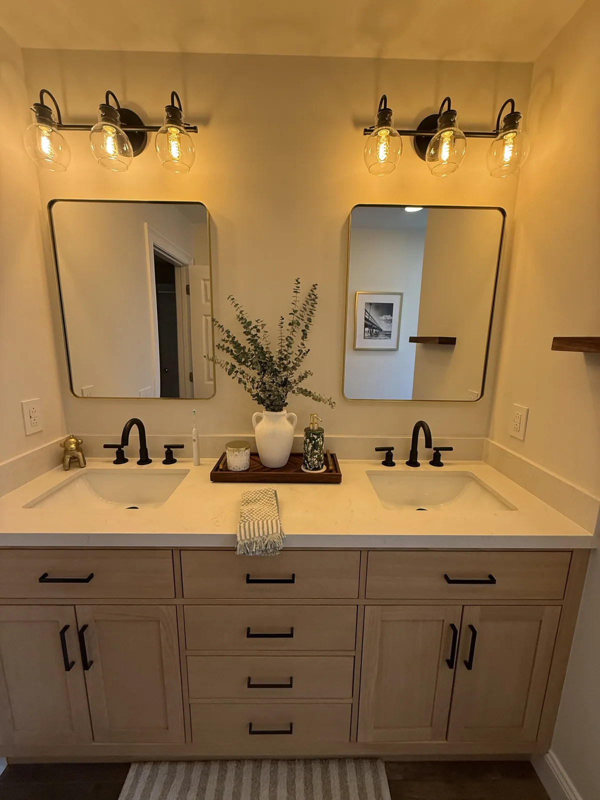 Double vanity with two mirrors, brass sconces and black fixtures