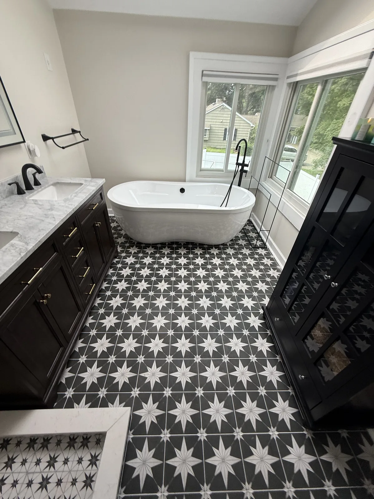 Bathroom with a freestanding tub, patterned tile floor, dark vanity and a skylight
