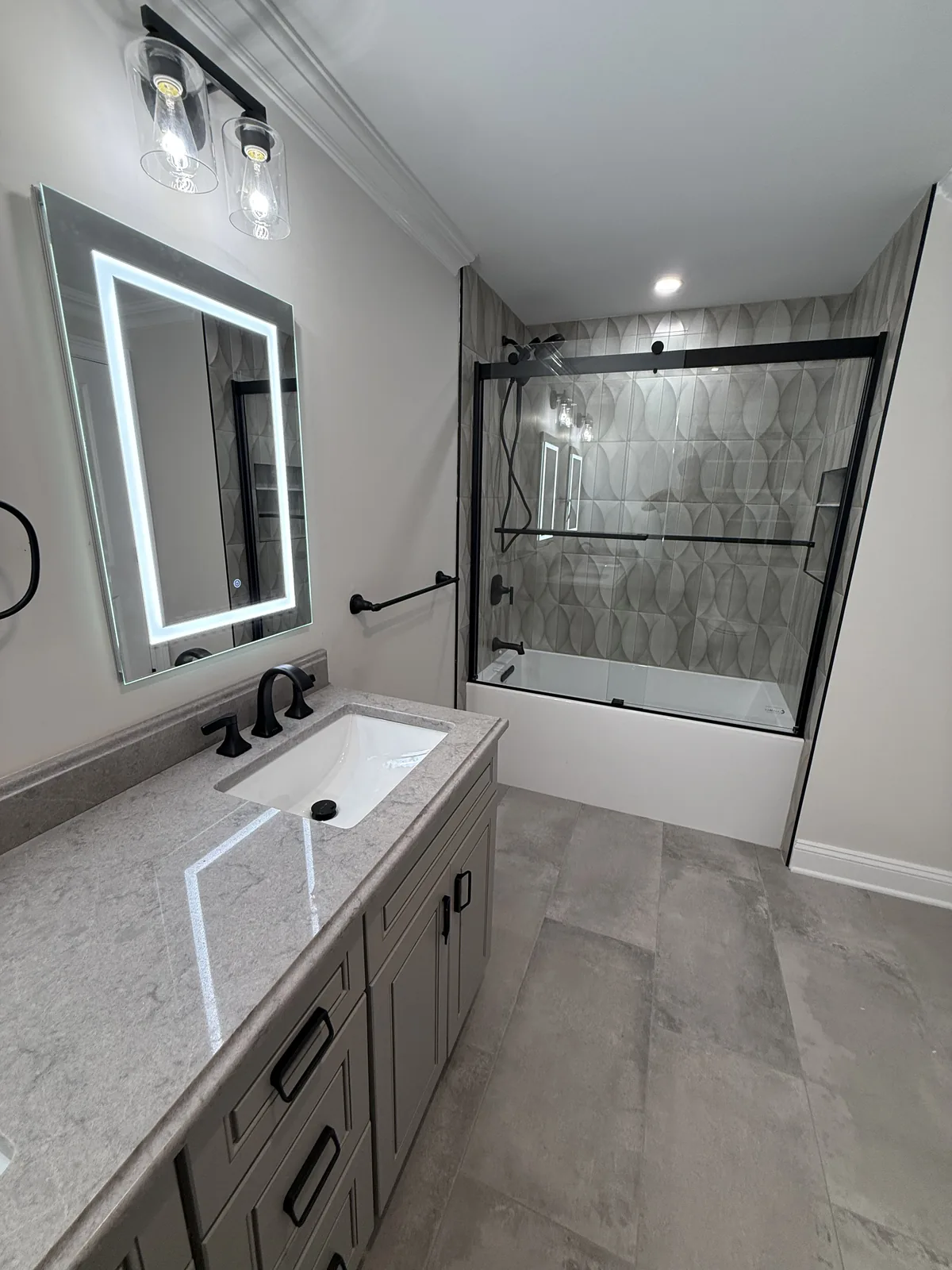 Bathroom vanity with a framed mirror, black fixtures and stone tile floor
