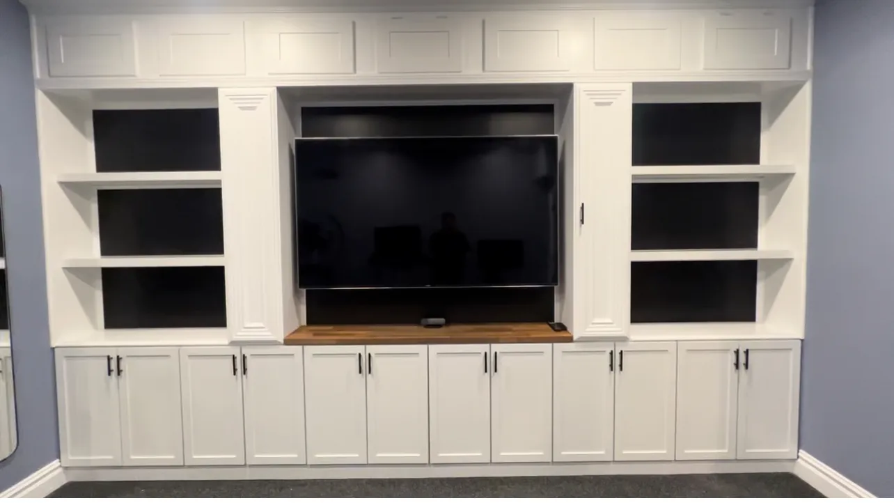 White built in cabinetry with open shelving either side of a recessed television