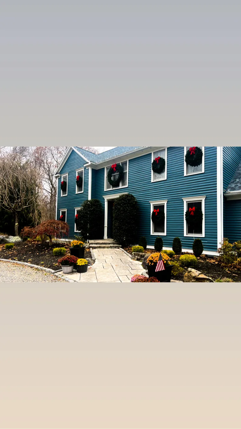 Blue colonial with white trim and autumn planting either side of the front door