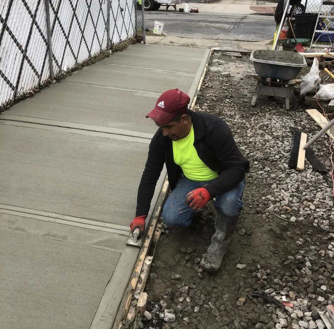 Worker kneeling to finish the edge of a freshly poured concrete slab
