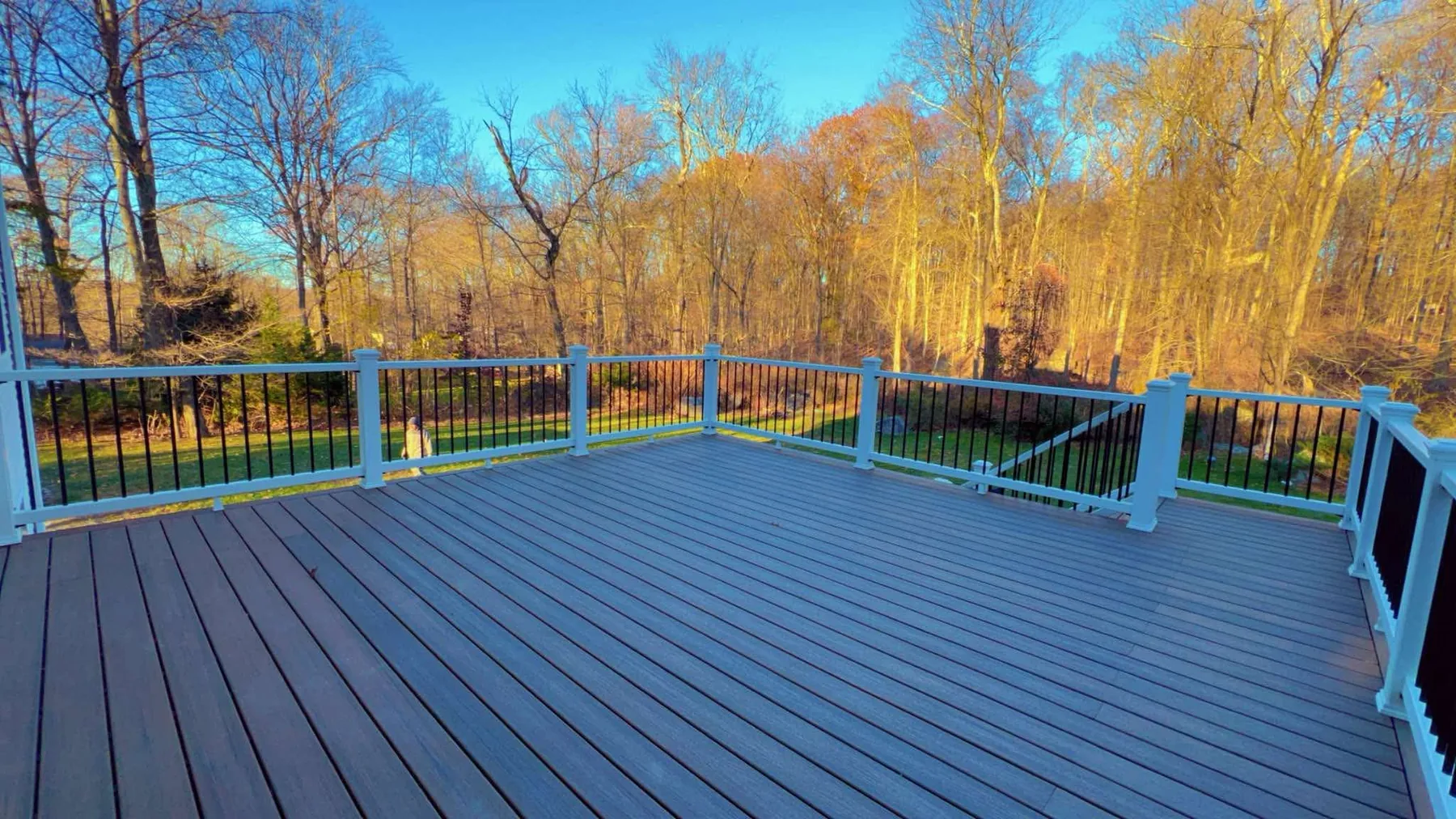 Composite deck with black railings backing onto autumn woods