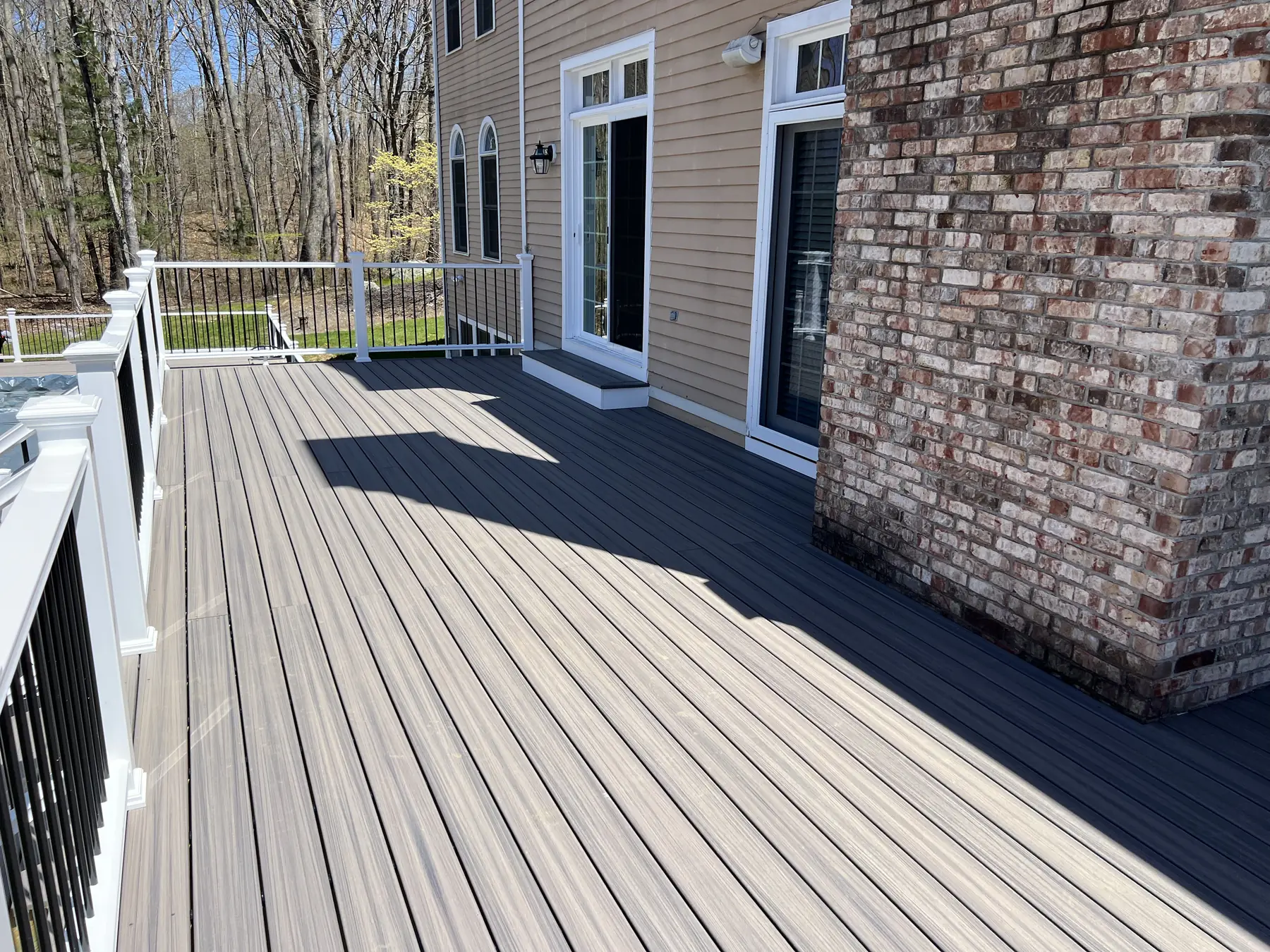 Composite deck wrapping an exposed brick chimney with white railings