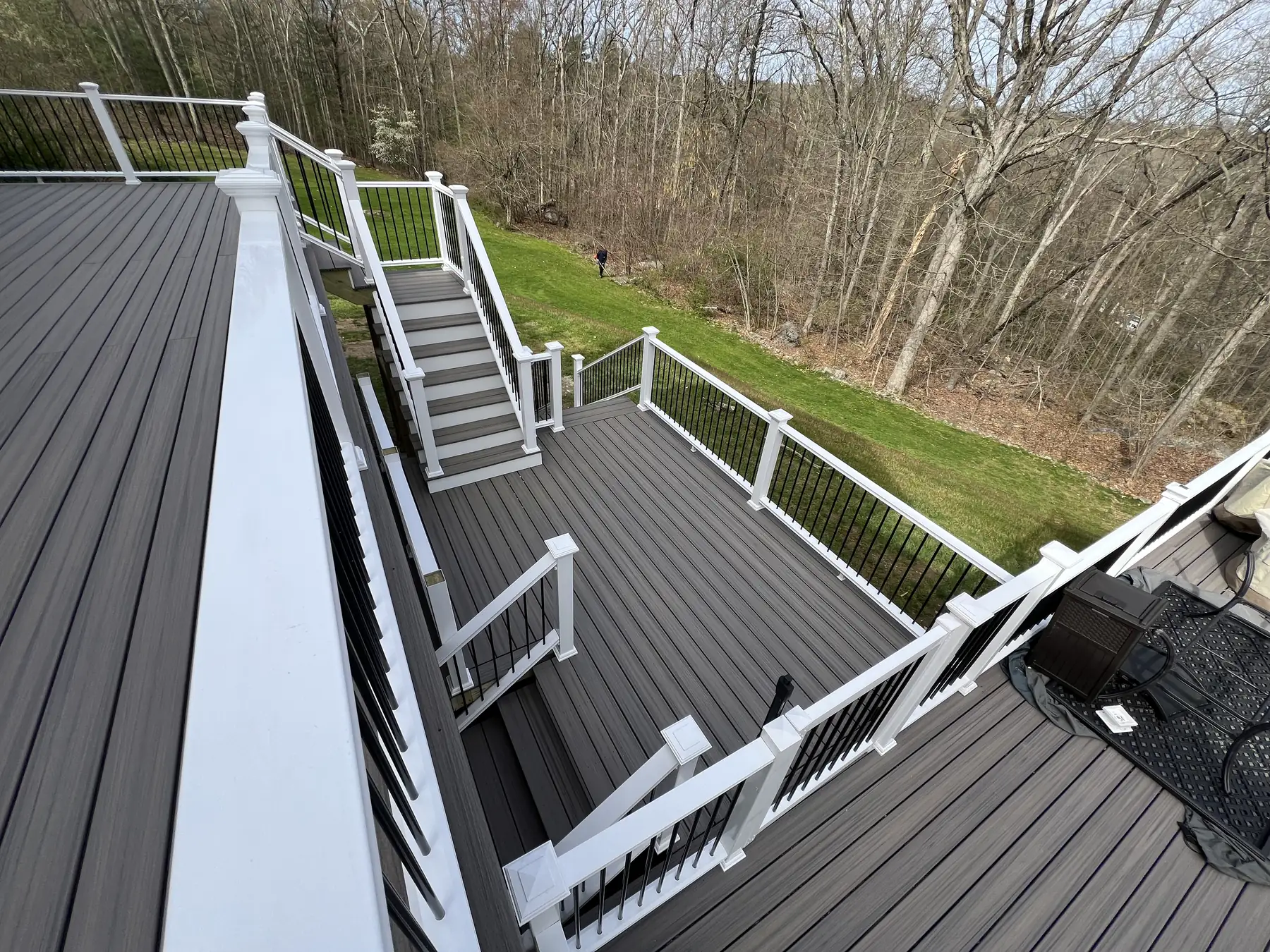 Gray composite deck with white railings and a staircase down to a wooded back yard