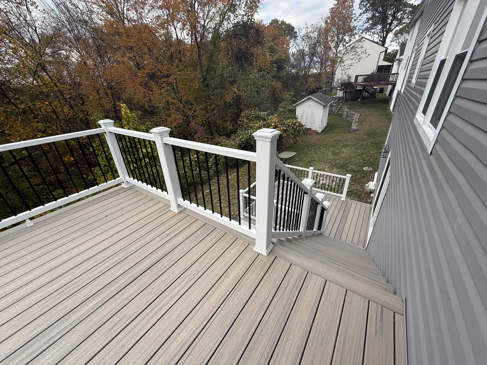 Composite deck with white posts and black balusters off the rear of a house