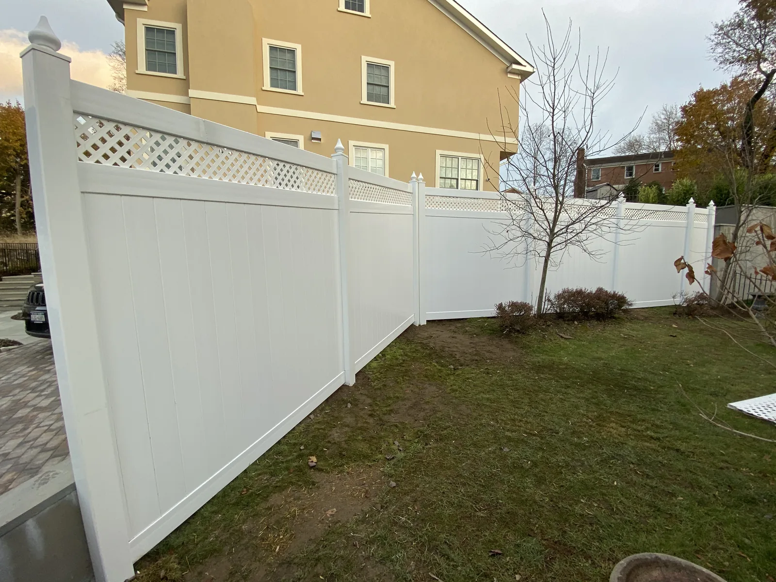 White vinyl fence along the side of a back lawn