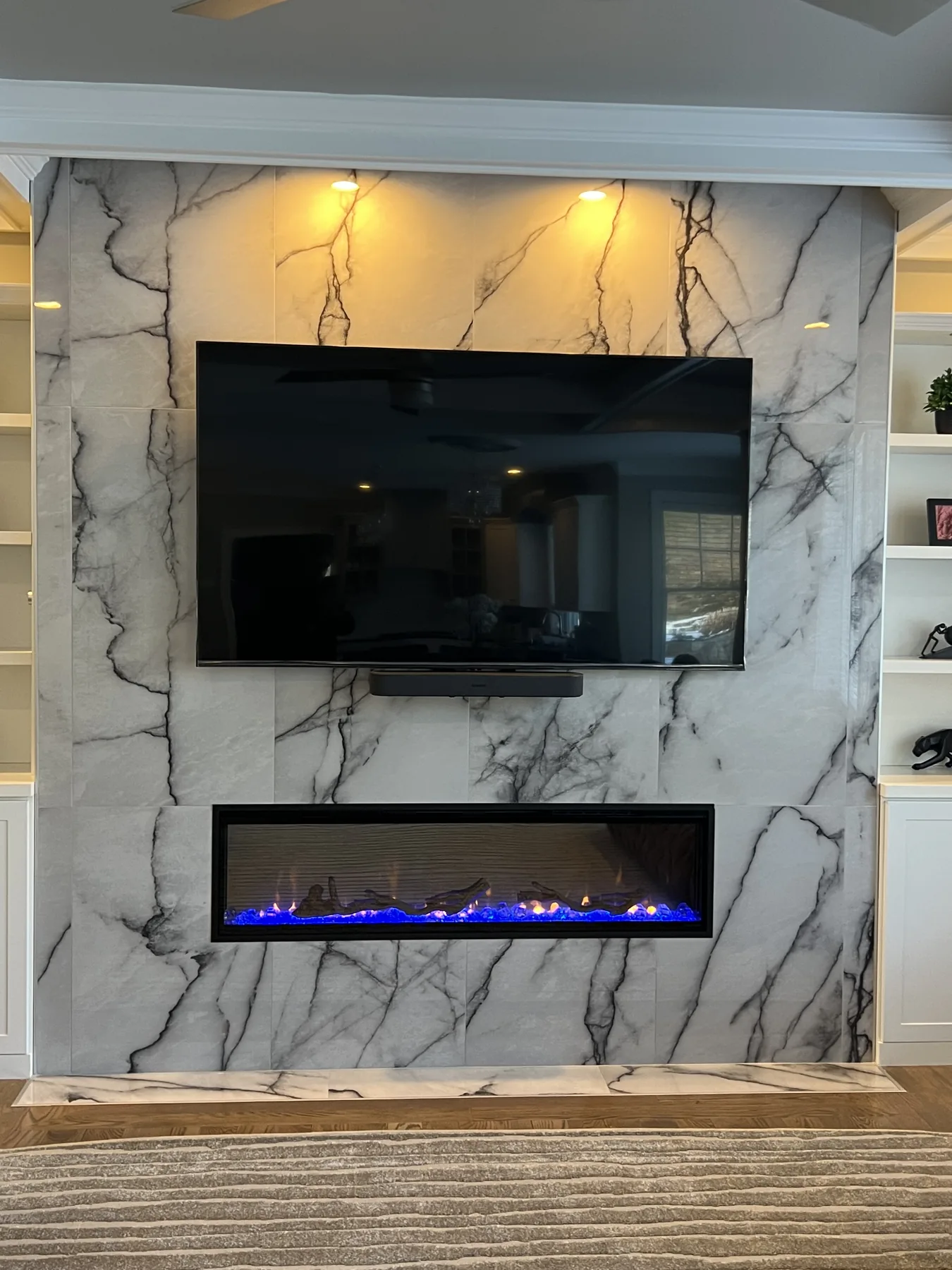 Floor to ceiling marble fireplace wall with a linear fireplace and a mounted television