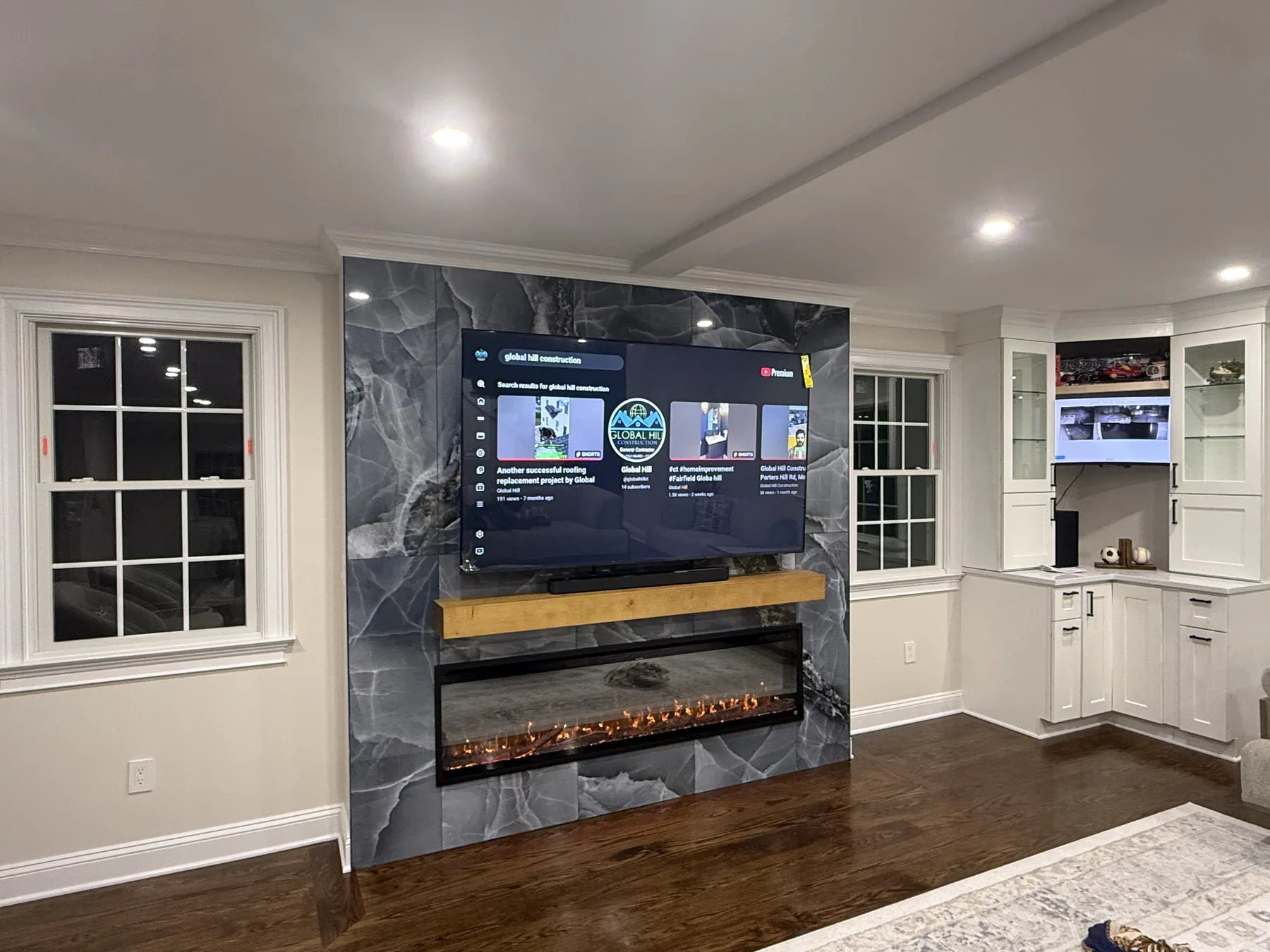 Living room with a marble fireplace wall, a linear fireplace and painted cabinetry