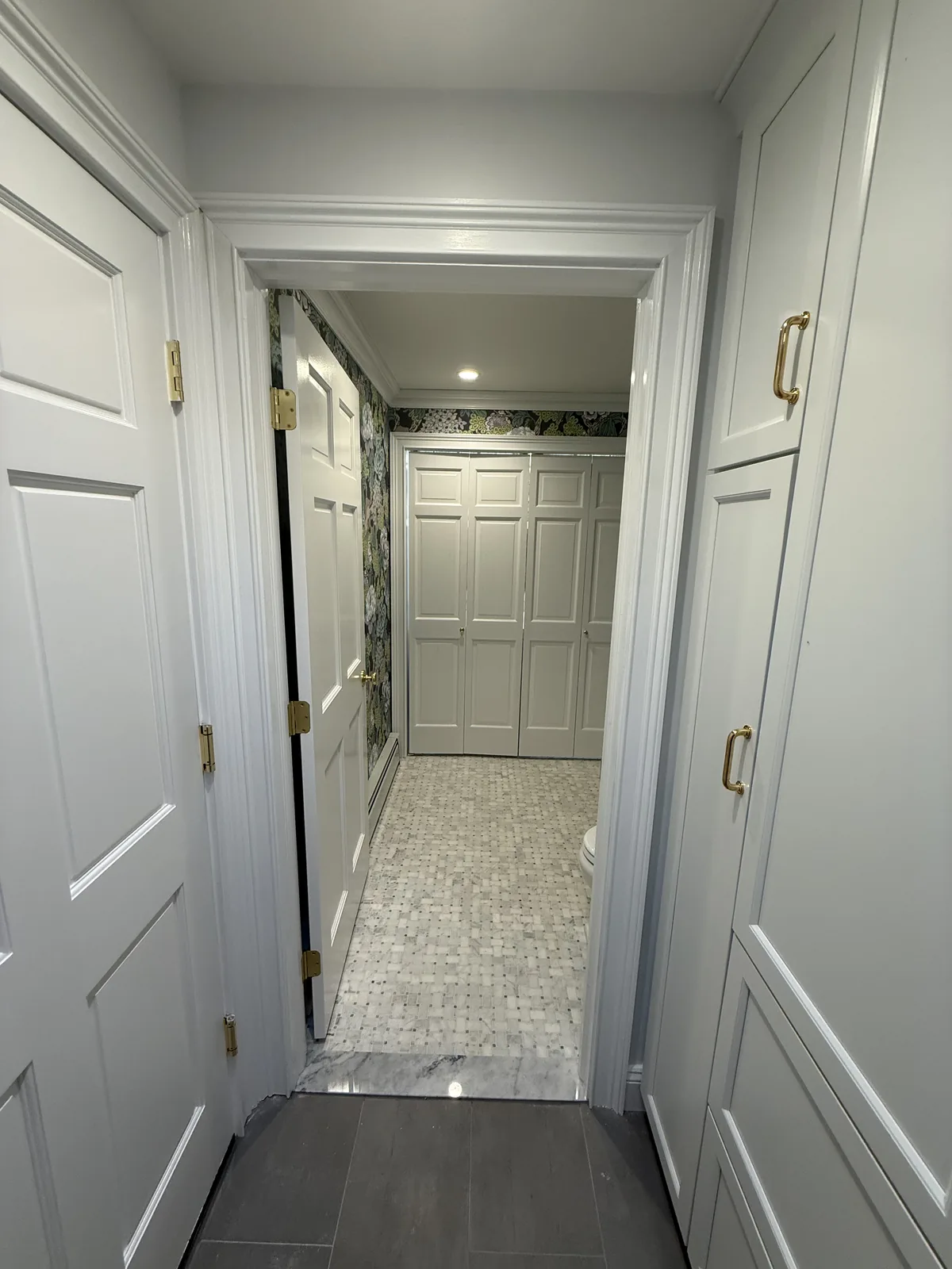 Hallway with a run of panelled doors and stone tile flooring