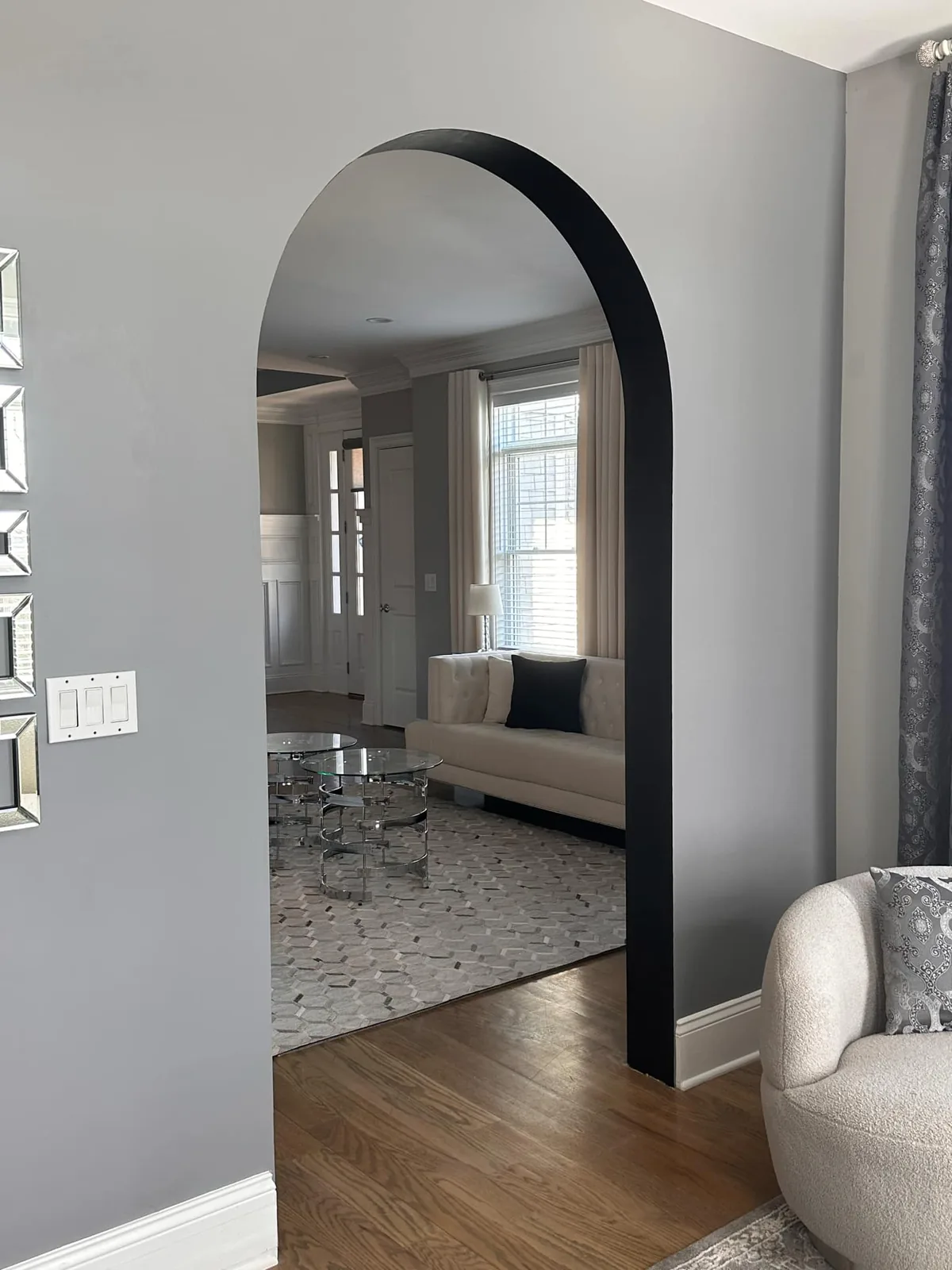 Plaster arched opening between a living room and a sitting room with hardwood floors
