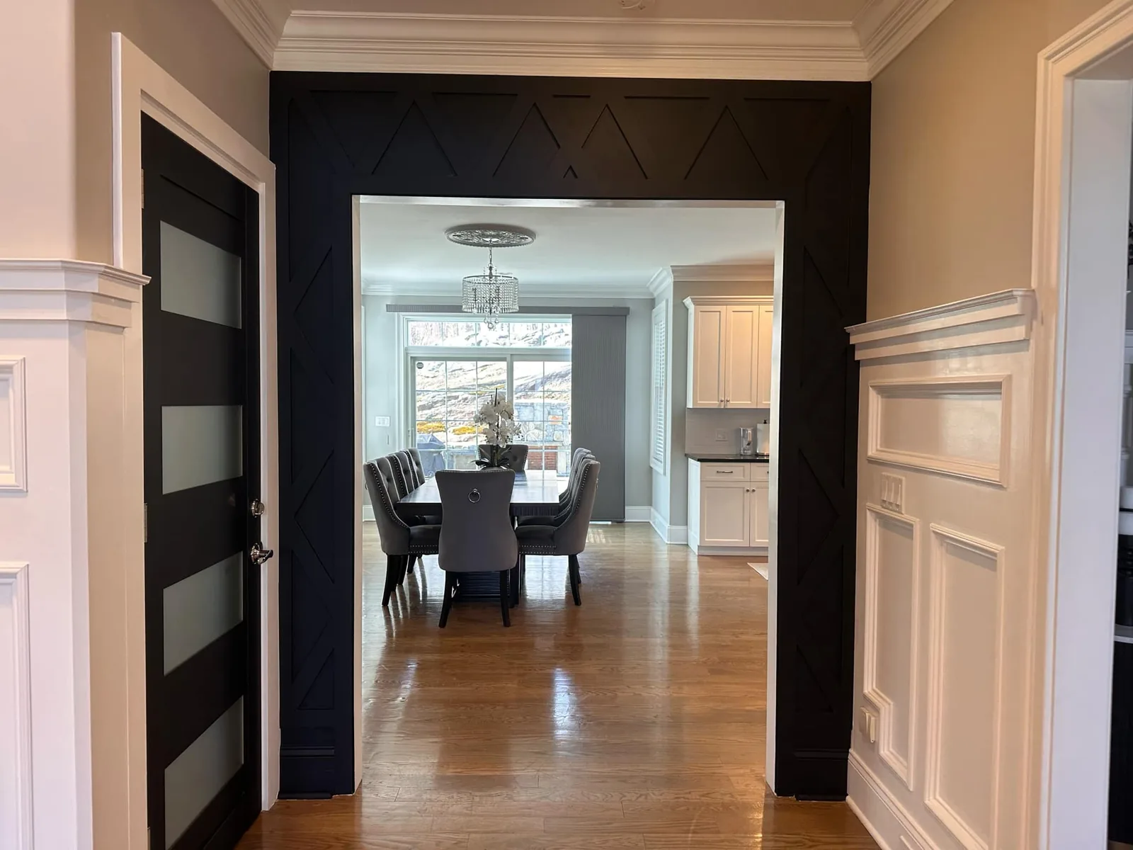 View through a dark panelled hallway into a bright dining room