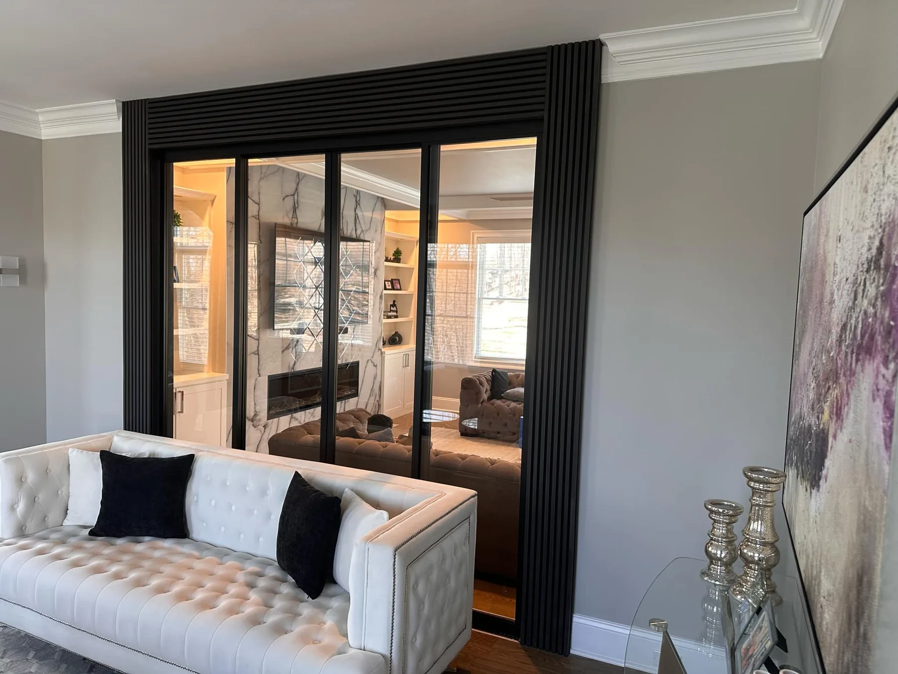 Living room with a pale sofa and black framed sliding doors into the next room