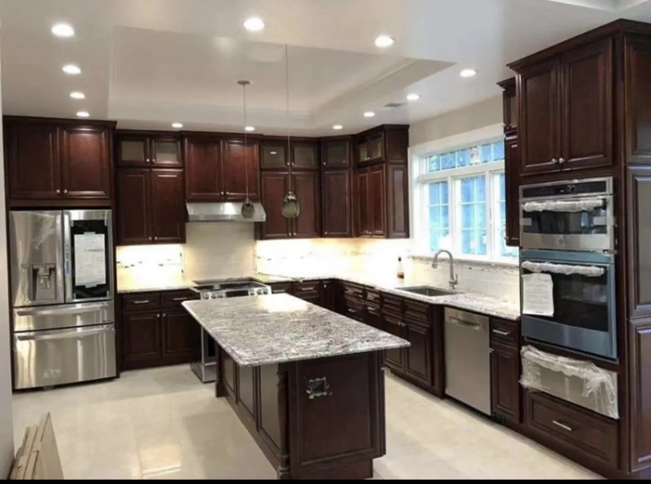 Kitchen with dark cherry cabinets, a granite island and stainless wall ovens