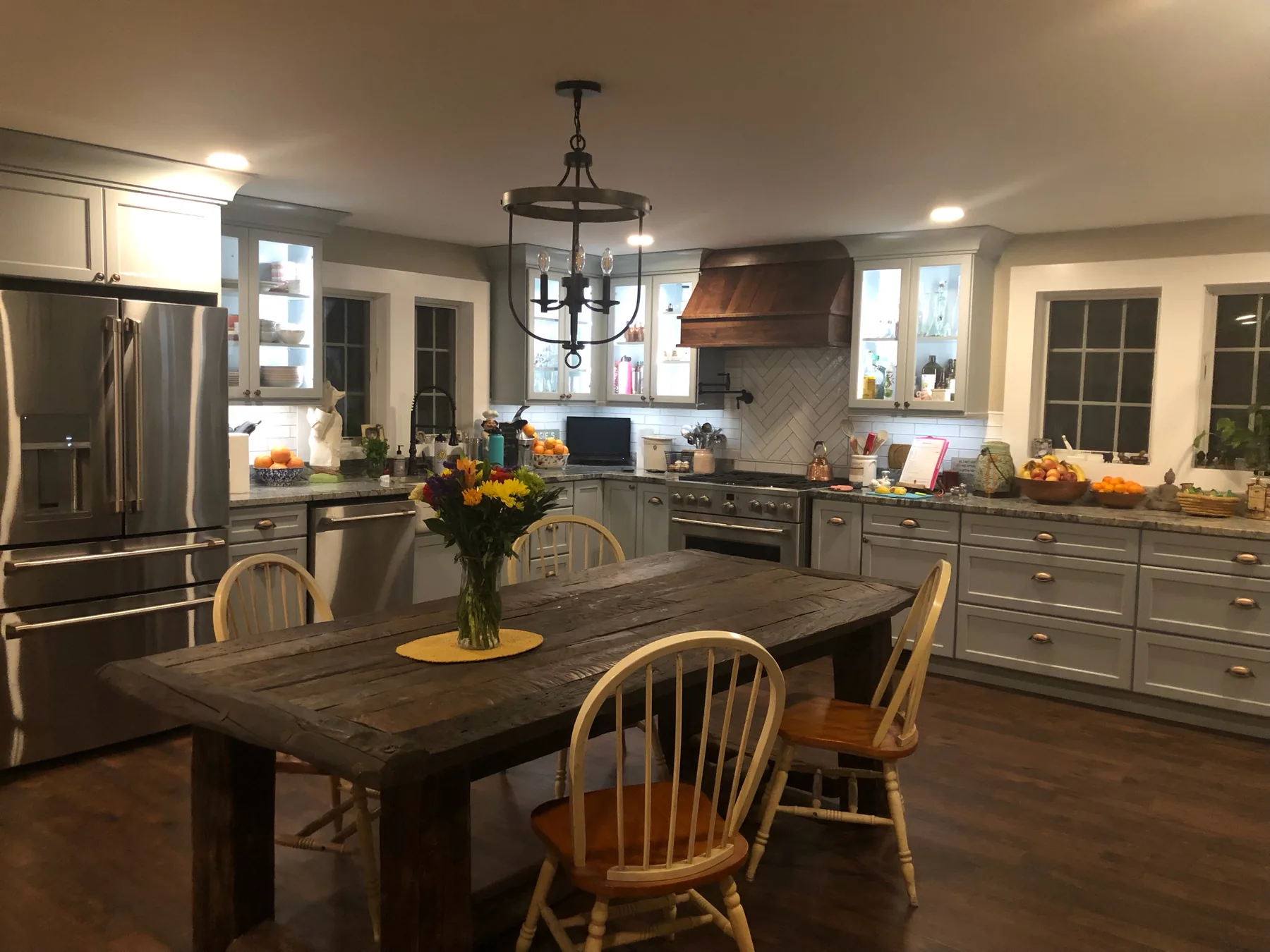 Kitchen with a wood dining table, black lantern pendants and a copper range hood