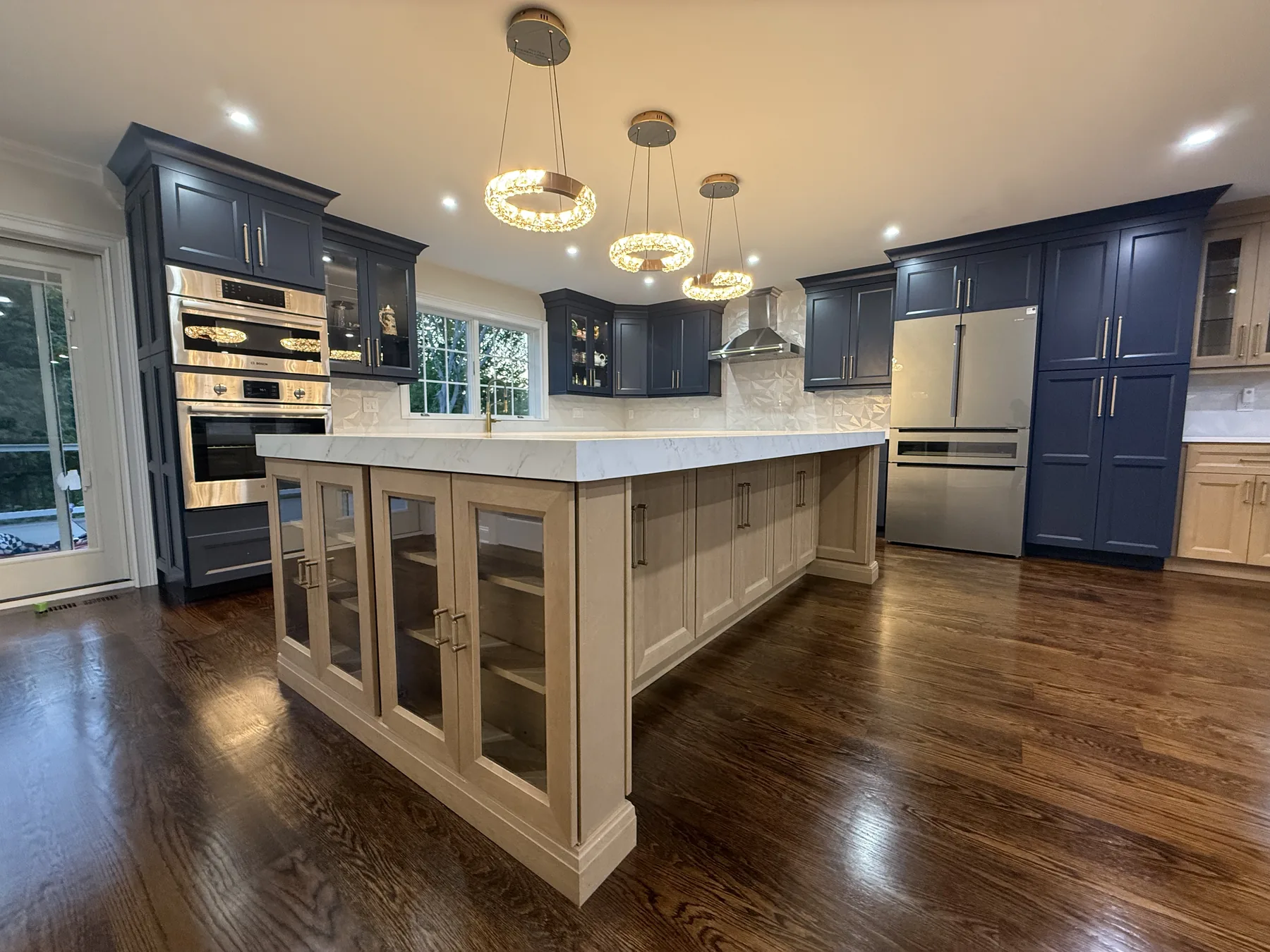 Kitchen with navy cabinets, a light island and stainless wall ovens