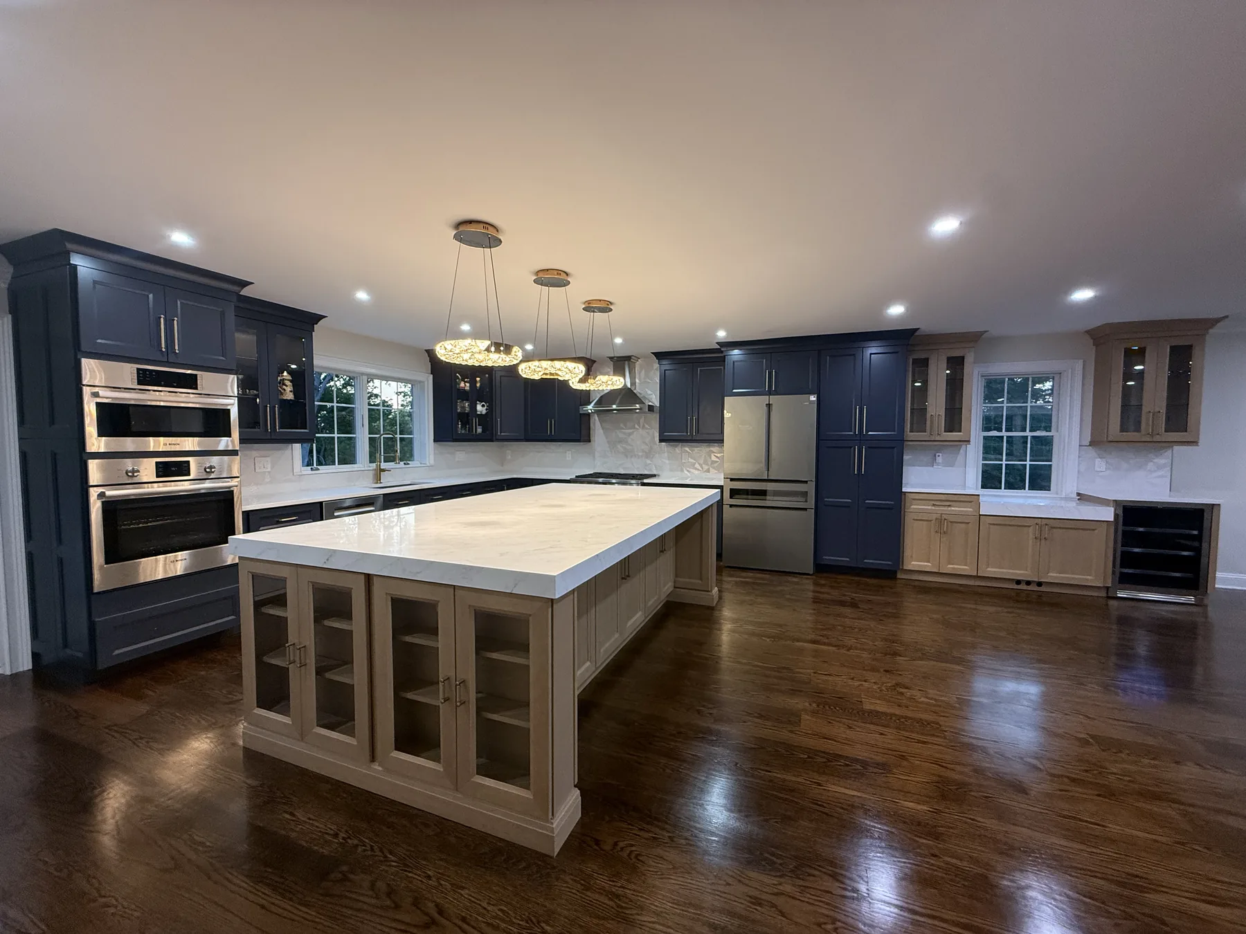 Remodelled kitchen with navy cabinets, a quartz island and wall ovens