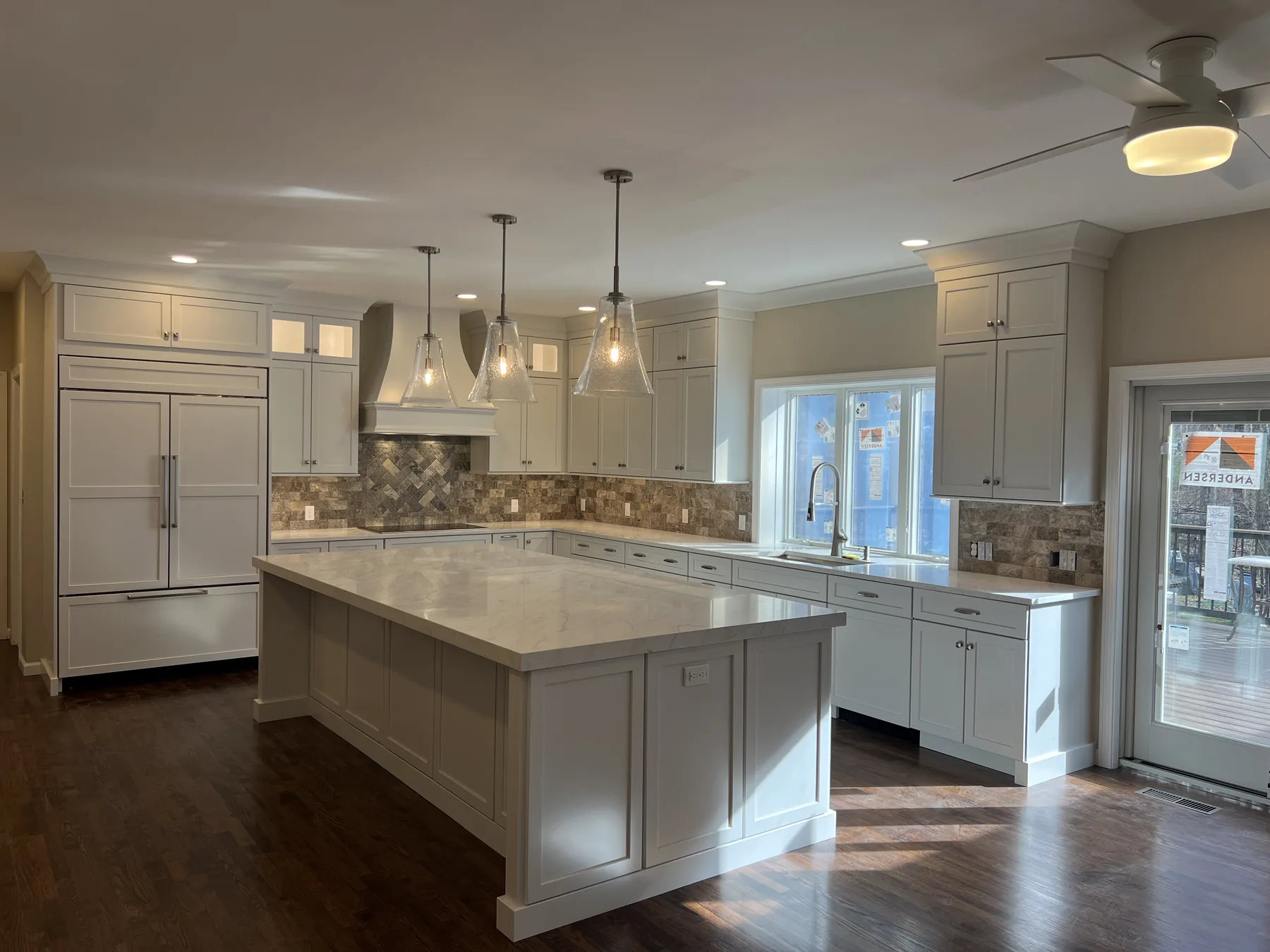 Kitchen with glass pendant lights over a quartz island and a panelled range hood