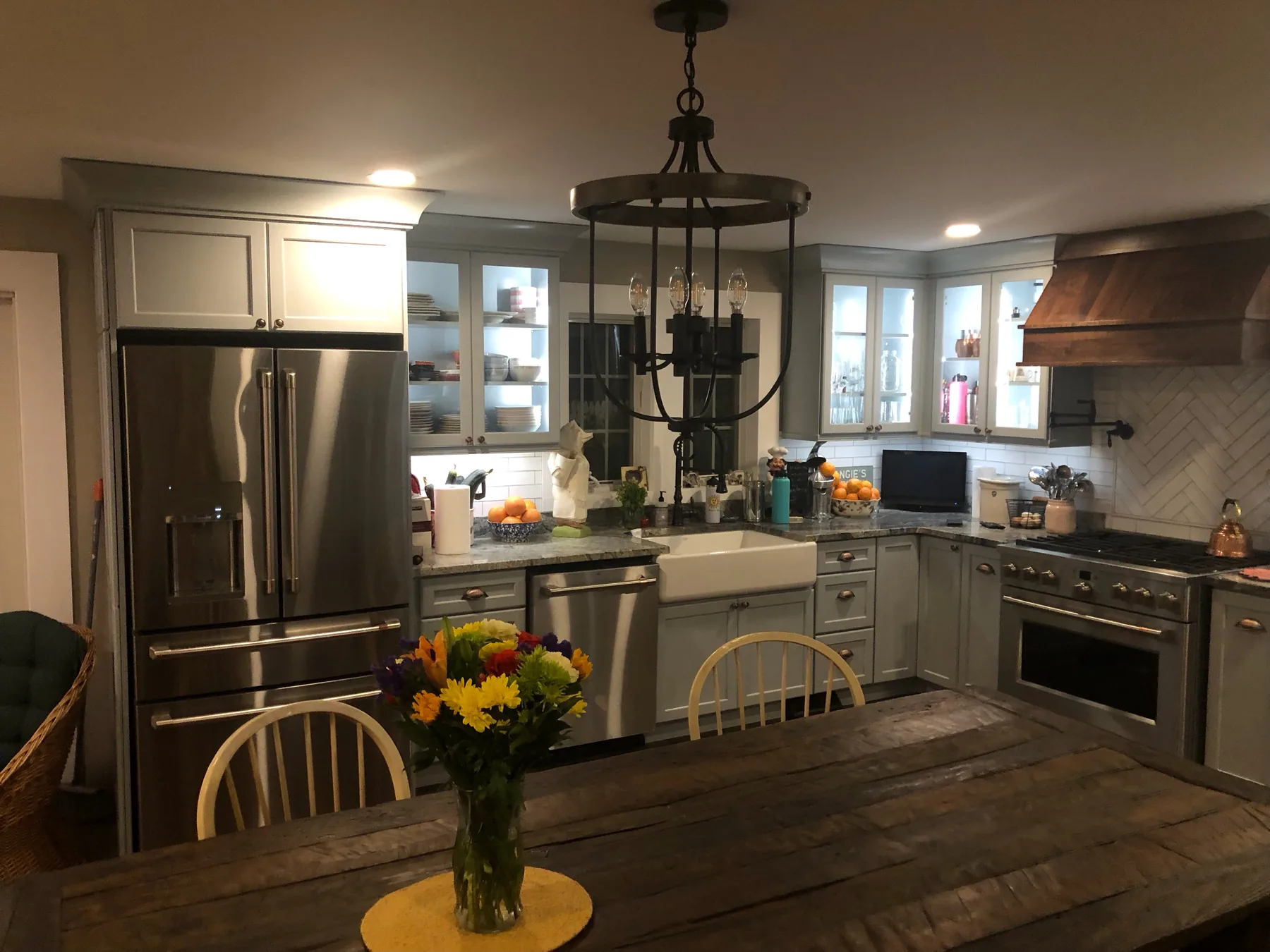 Kitchen with a copper range hood, black lantern pendants and a wood dining table
