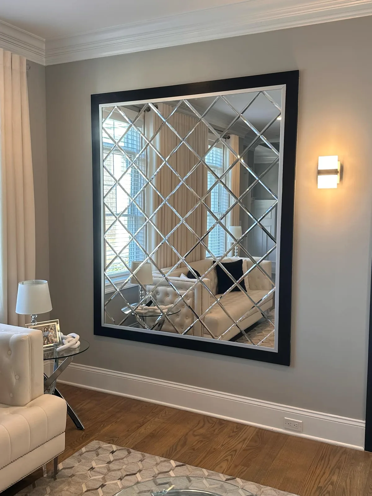 Living room with a large framed mirror, a wall light and pale furniture