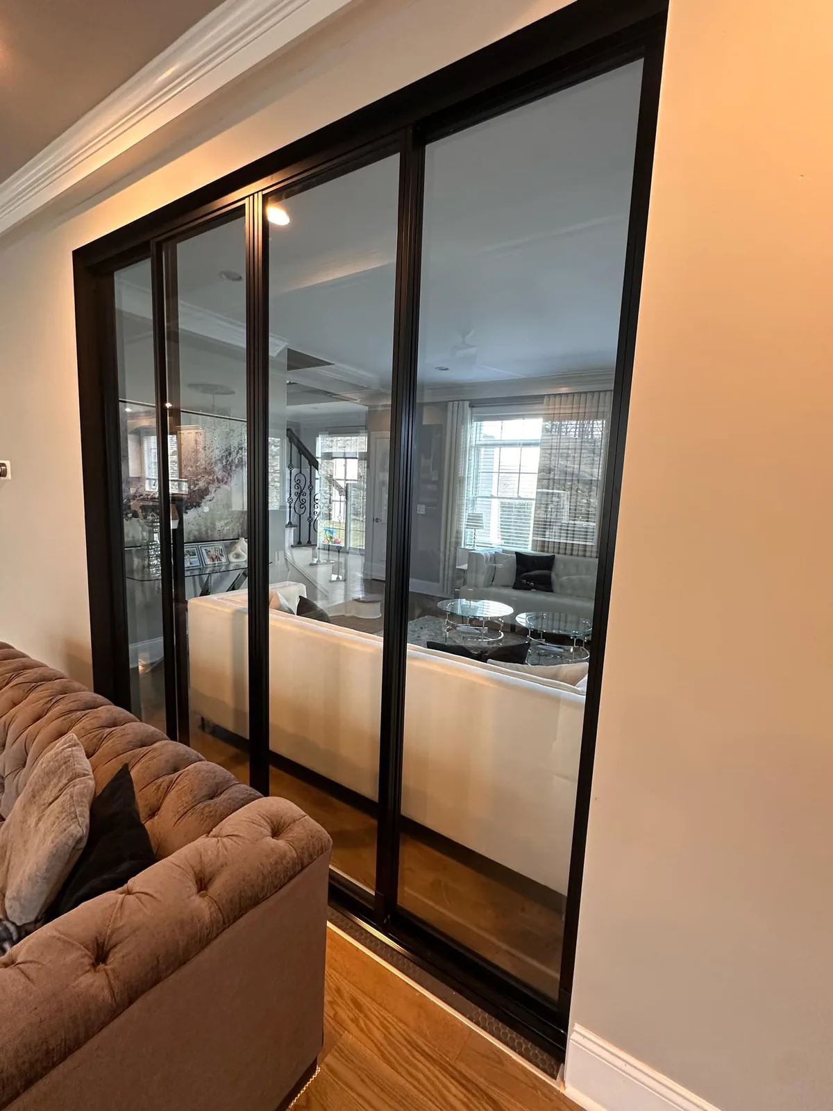 Living room with black framed mirrored sliding doors and hardwood floors