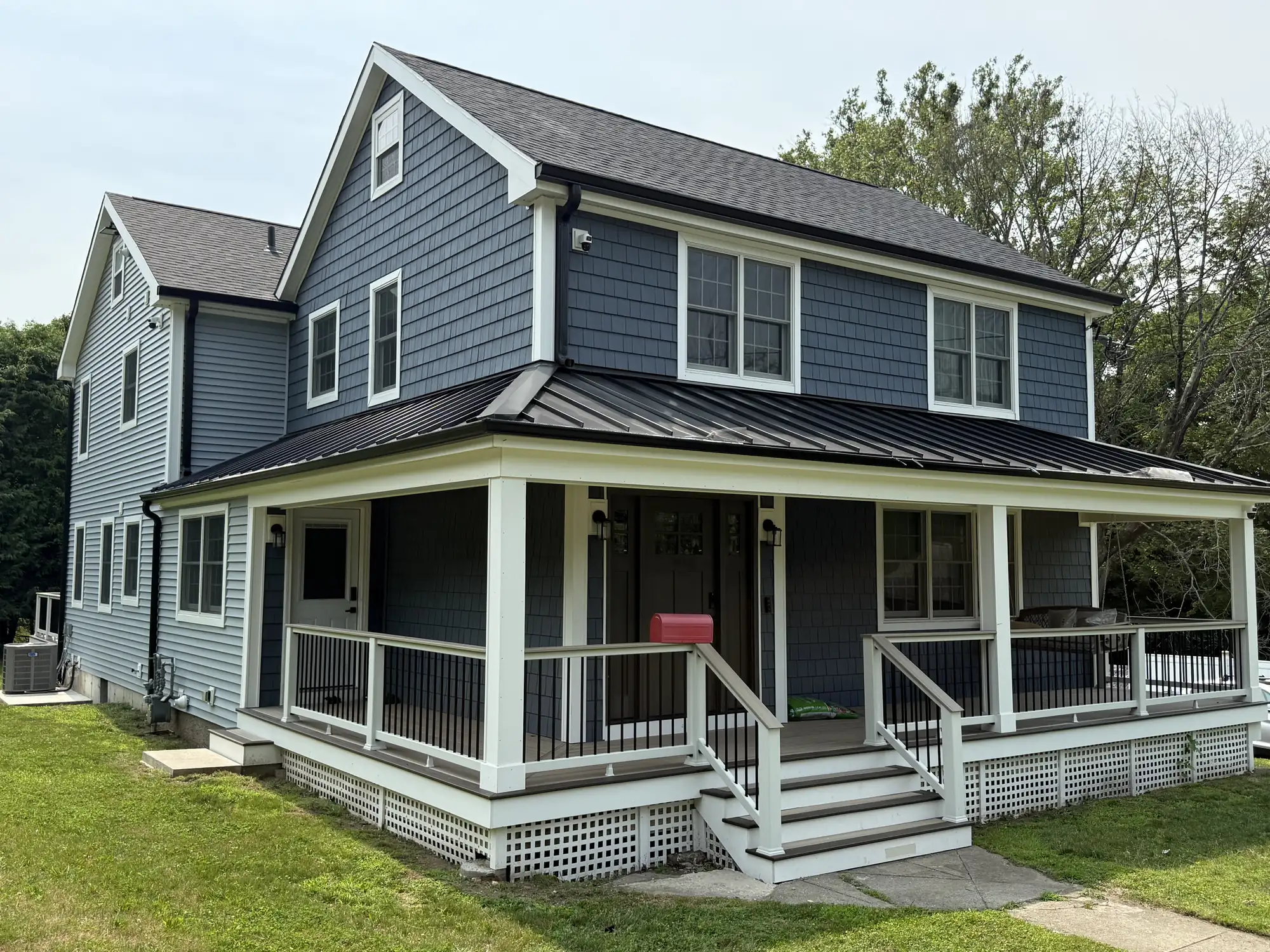 New custom home with a wraparound porch and a standing seam metal roof