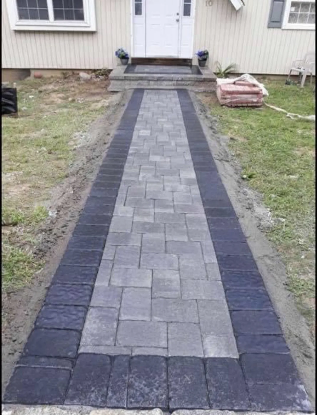Paver walkway leading to a front door with a stone border