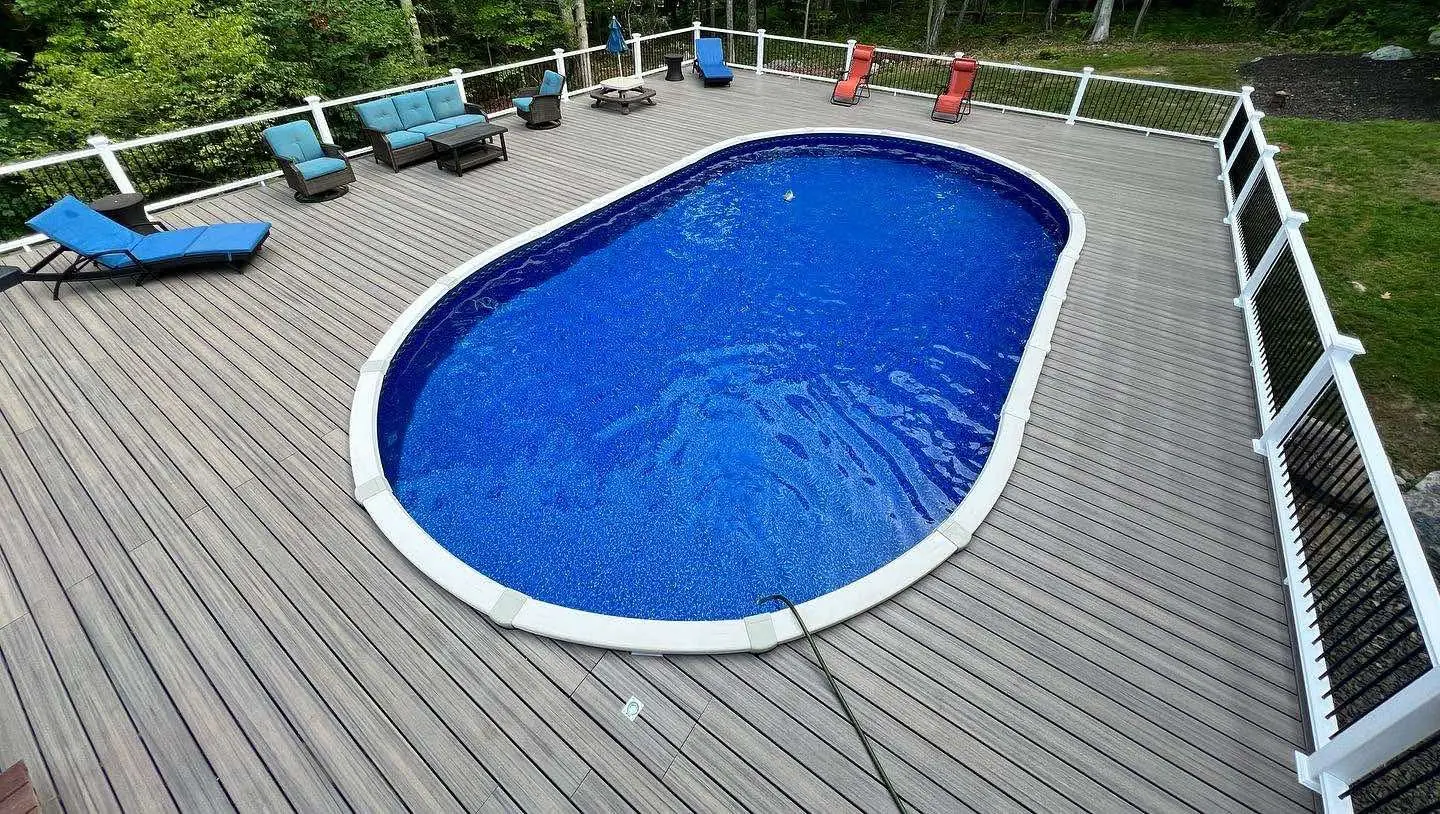 Composite pool deck with loungers and railings around an above ground pool
