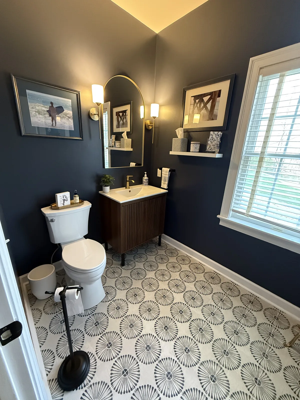 Powder room with navy walls, patterned floor tile and a wood vanity