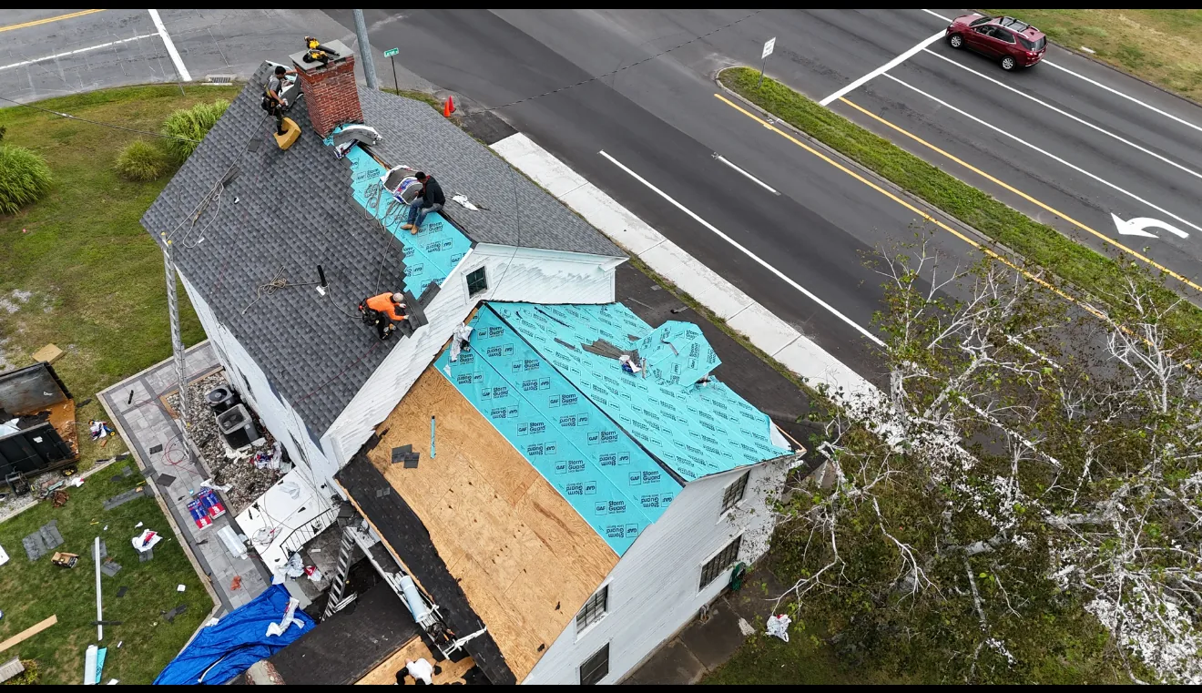 Aerial view of a roof replacement with underlayment down and bundles of shingles stacked