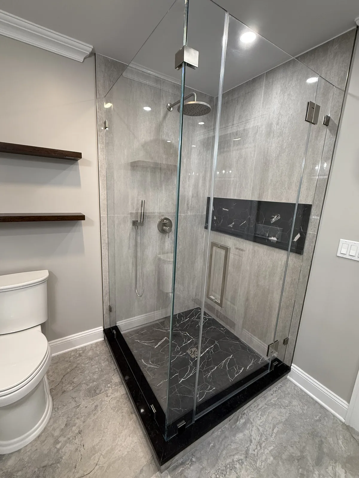 Corner shower with veined tile, a black base and frameless glass