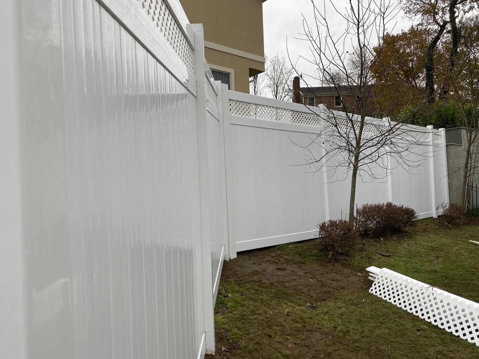 White vinyl privacy fence along the edge of a back lawn